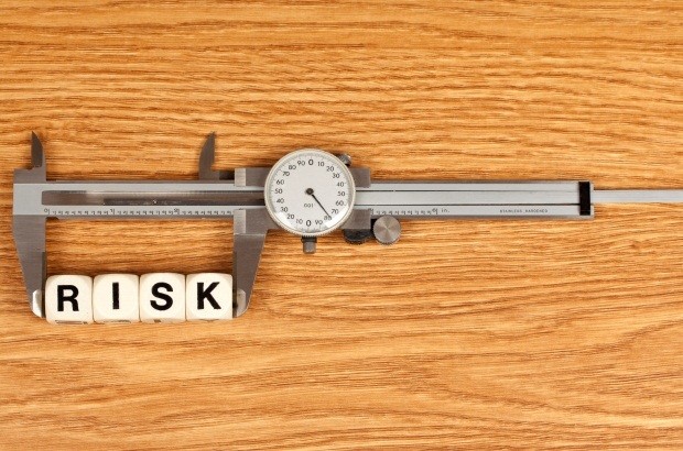 Scrabble pieces spelling out the word risk placed in a measure to detail measuring and managing risk