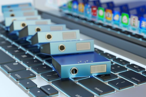 Office paperwork, pile of blue ring binders on laptop keyboard