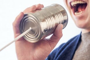 Individual speaking into a tin can acting as an acoustic speech-transmitting device.