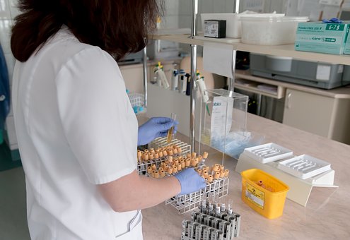 Technician in laboratory with batches of test tubes.