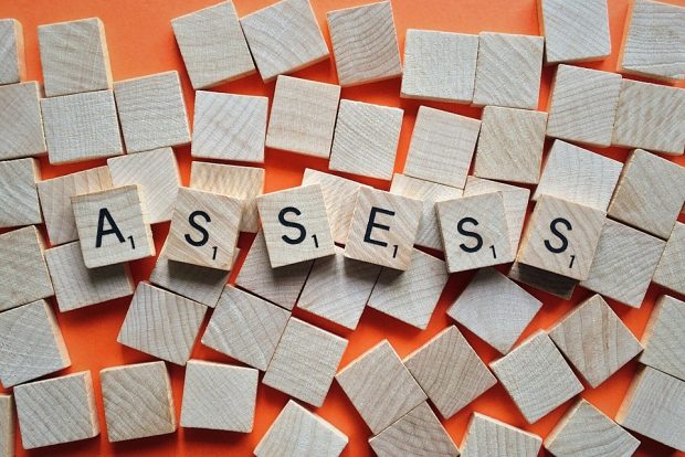 an arrangement of scrabble tiles spelling out the word 'ASSESS'