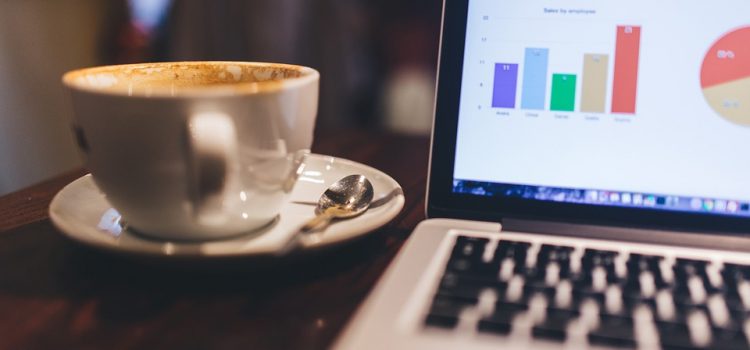 coffee cup next to open laptop displaying bar chart