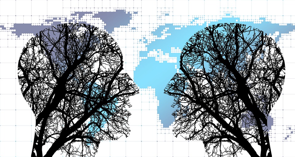 2 heads, silhouetted against a world map, engaged in dialogue