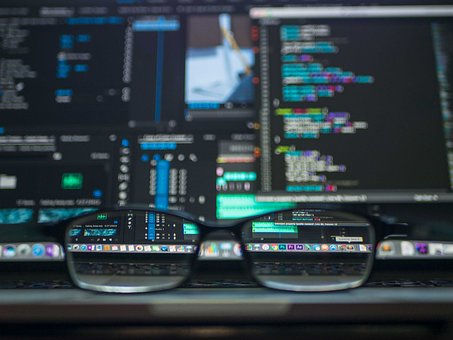 A pair of spectacles in front of a computer screen representing careful scrutiny of data