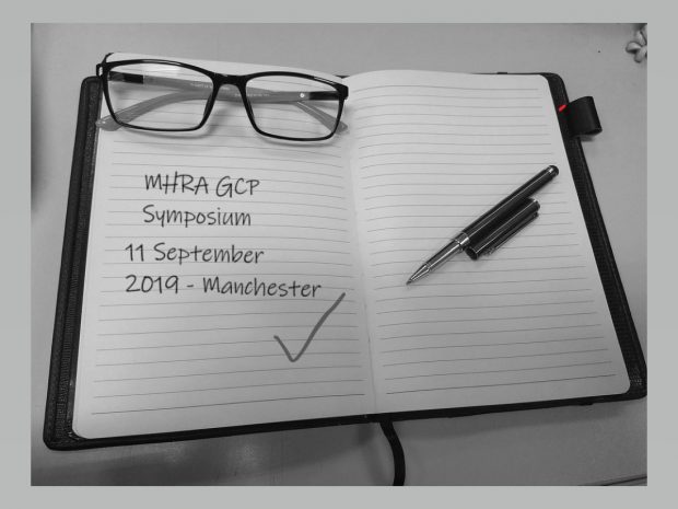 Open notebook. Written on the page is: MHRA GCP Symposium, 11 September 2019, Manchester