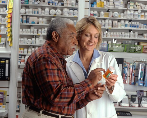 Gentleman consulting with a pharmacist about the medicine she is holding